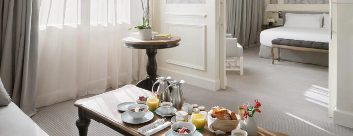 050-junior-suite-city-view-salon-elegante-con-sofa-claro-mesa-madera-desayuno-y-orquidea-natural.jpg