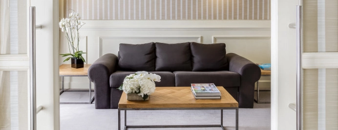 01-junior-suite-paseo-de-gracia-sala-estar-con-sofa-oscuro-mesa-centro-y-decoracion-floral.jpg